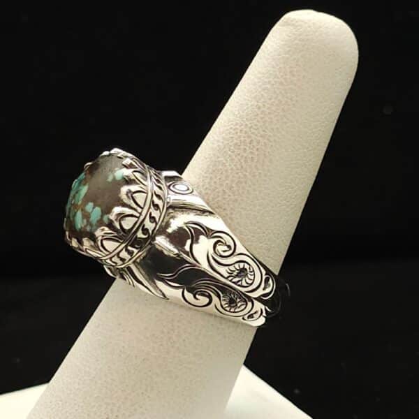 "A sterling silver ring featuring an oval Chinese turquoise stone, detailed bezel, and carving on the shank, size 8, part of the Ethnographic line by Turquoise Deluxe."