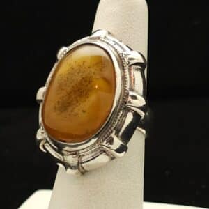 "A sterling silver ring featuring a natural Baltic amber stone with a detailed band, size 7, part of the Ethnographic line by Turquoise Deluxe."