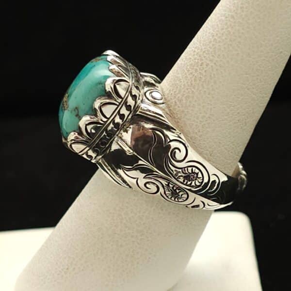 "A sterling silver ring featuring a cushion Chinese blue cabochon with chert matrix, ornate bezel, and carved band, size 8, part of the Ethnographic line by Turquoise Deluxe."